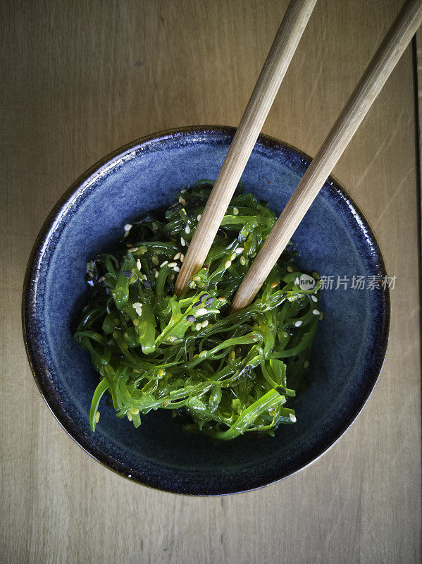 木桌上的碗里盛着日式紫菜沙拉