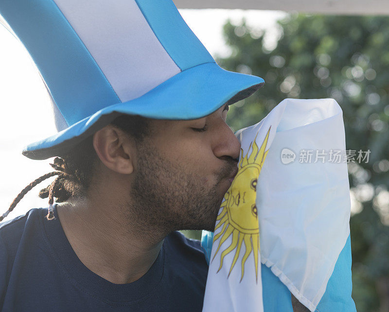 幸福的阿根廷人的肖像与帽子和国旗庆祝世界杯