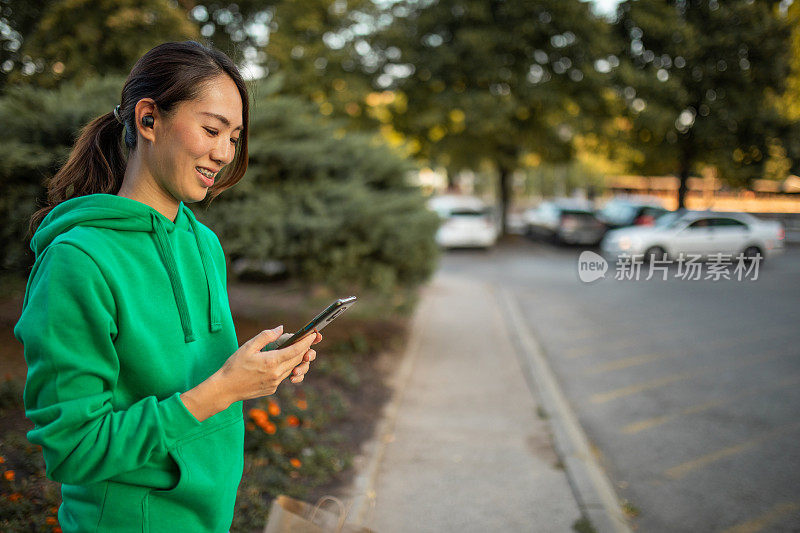 在城市里，一名妇女一边走路一边用手机发短信