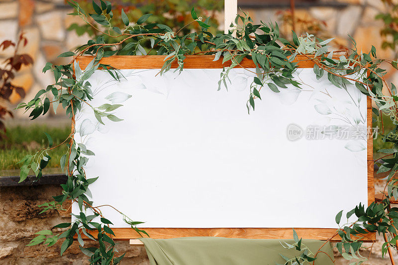 婚礼木板，模型，邀请画架，留白题字，用新鲜的绿色植物和绿色布装饰。户外婚礼帧。节日装饰，复制空间。