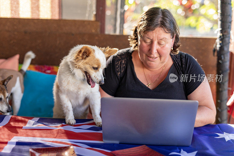 快乐的成熟女人用电脑和她的狗