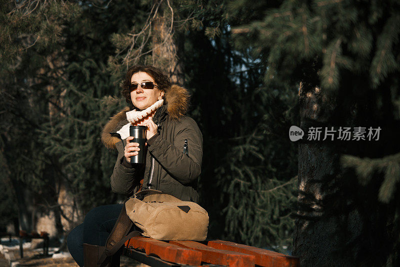 冬天的自然公园里，一名女子正在喝热茶