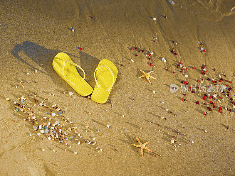 黄色的沙滩拖鞋站在沙滩上。