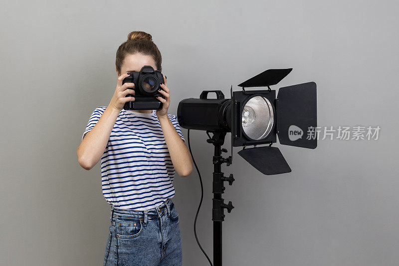 妇女在照相馆拍照，使用照相机和反光镜。
