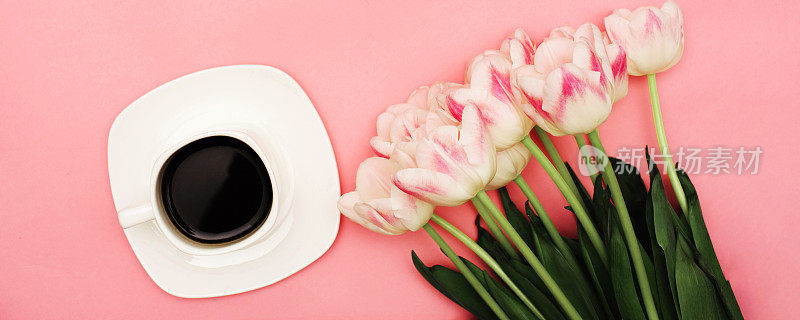 一束美丽的精致的粉红色郁金香旁边的一杯咖啡在粉红色的背景。这可能是你的短信。横宽照片字幕，封面。copy-space