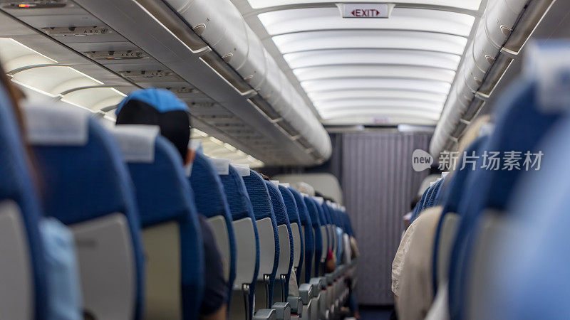 乘客座位。飞机内部，乘客坐在座位上。飞机客舱。机舱:有乘客坐在座位上的飞机内部