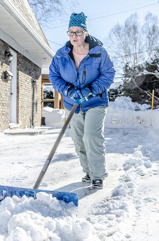 成熟女子用铲子推雪