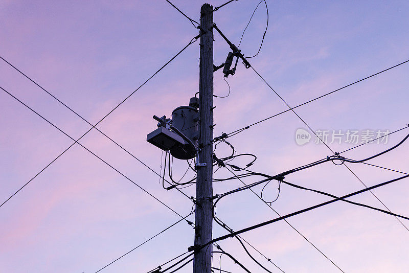夏季傍晚天空前的电力线、互联网电缆和有线电视通讯。