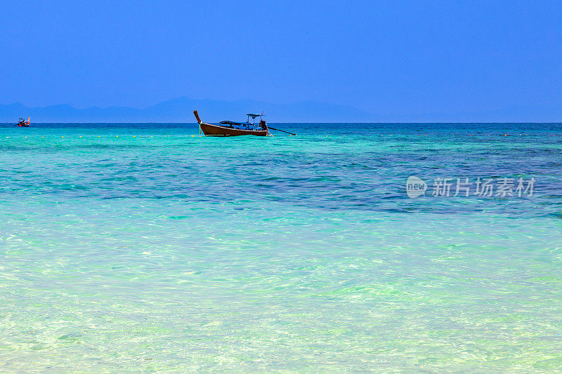 这是一艘古老的泰国传统摩托艇，由木头制成，用于钓鱼和运送游客在安达曼海蔚蓝的天空下畅游碧绿的海水。在普吉岛旅游度假。