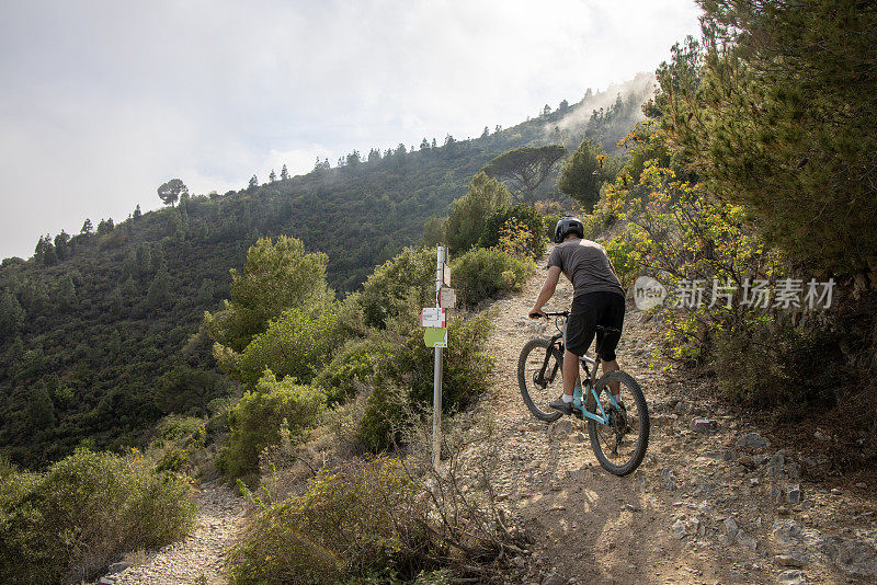 男性山地自行车手爬过山间的岩石小路