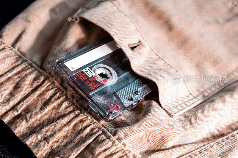 复古的动感:米色裤子口袋里的卡带特写