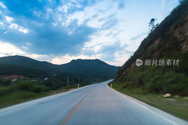 乡村高速公路动态模糊拍摄与汽车钻机接近黄昏