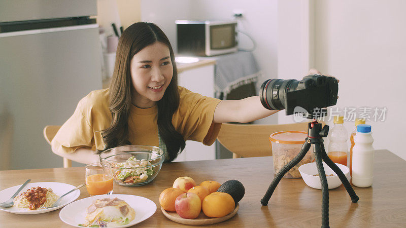 专业美丽的博主网红录制视频制作沙拉水果和蔬菜，同时在家里的厨房做饭。