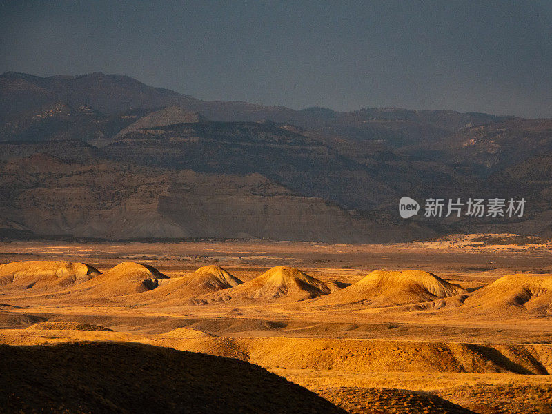 夕阳落在犹他州绿河沙漠的山丘上。