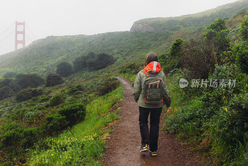 一名女子走在旧金山金门大桥的小山上