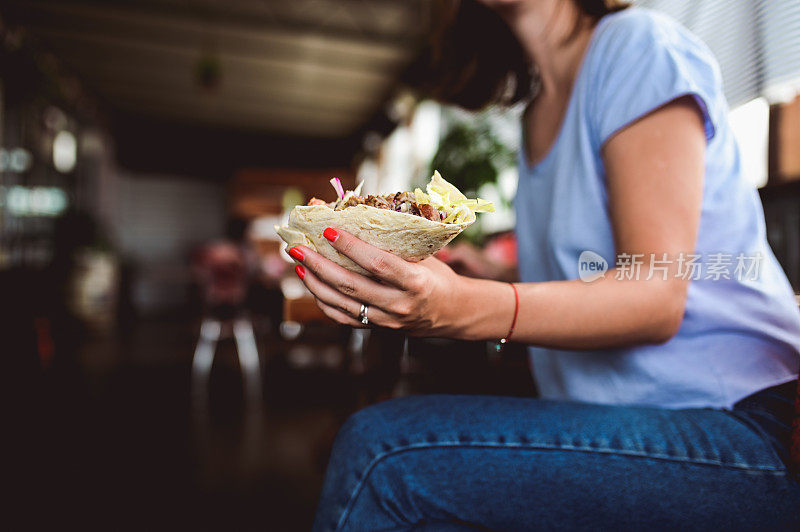 一名妇女在快餐店吃着硬面包串。