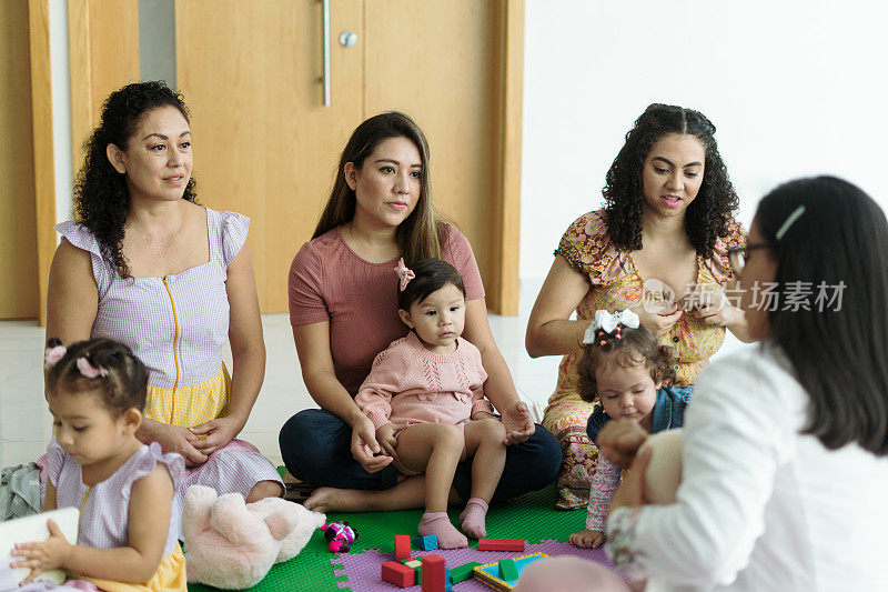 三位母亲和她们的孩子在认真地听母乳喂养课。