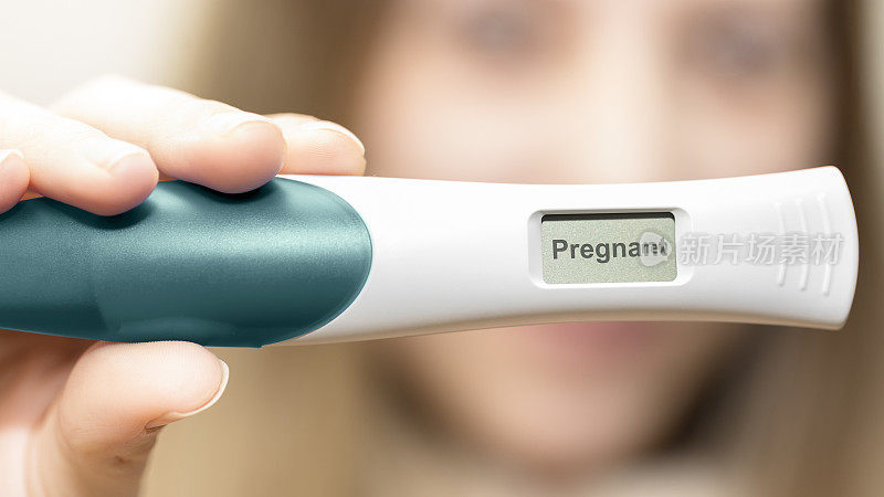 一名孕妇在镜头前的妊娠测试呈阳性。近距离观察怀孕测试与单词怀孕。产前检查