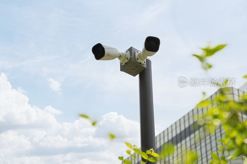 闭路电视摄像机，两个高清晰度的安全摄像机安装在银行前面的杆子上。
