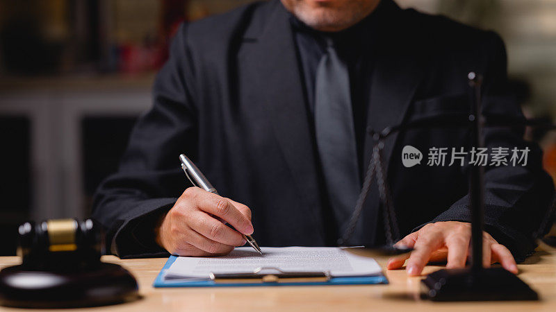 西装革履的律师或法官正在一张纸上写字。他系着领带，在一个专业的场合