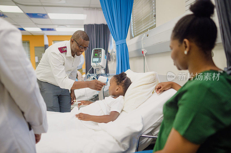 可爱的非洲小女孩躺在病房的病床上，男护士用红外体温计给她量体温