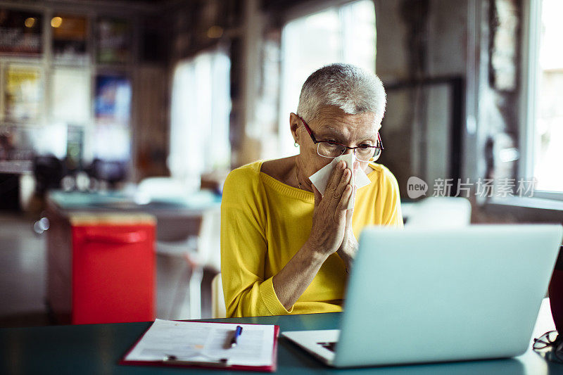 年长的女士用纸巾擤鼻涕