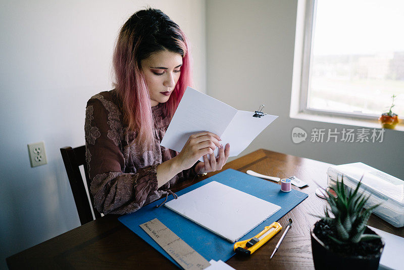 粉红色头发的女孩在家里做书籍装订