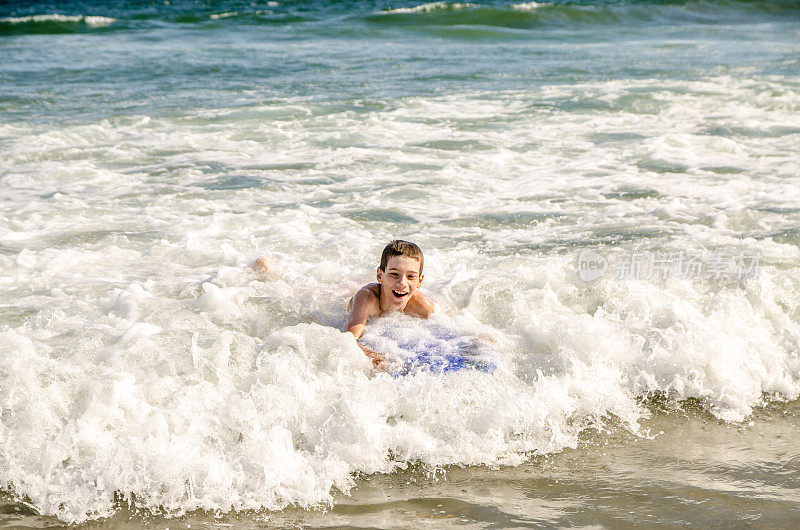 小男孩带着小冲浪板在海滩上