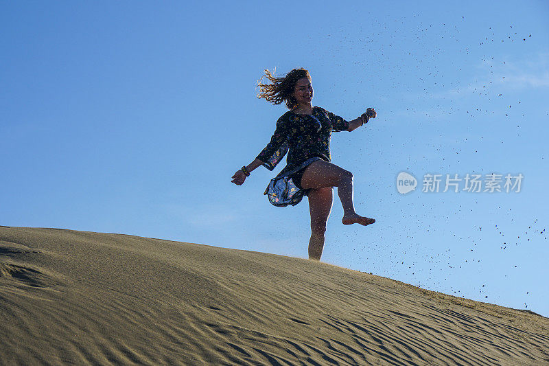 一个年轻漂亮的女人走在沙丘上。