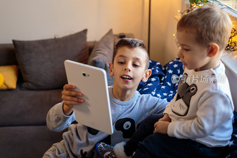 一个小男孩正在向他的弟弟展示一个数字平板电脑上的东西