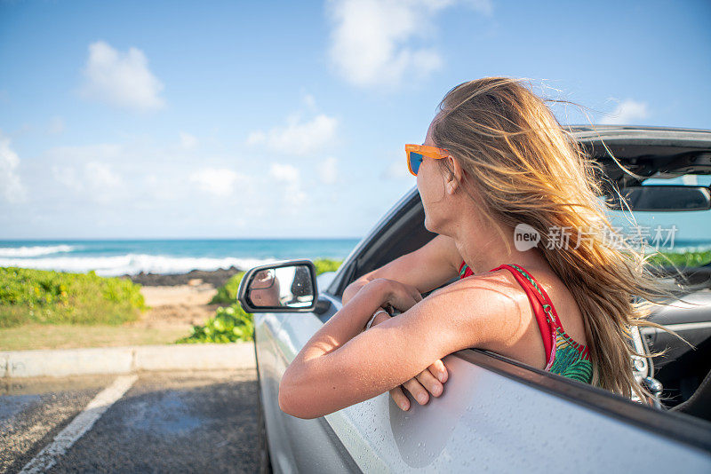 金发女人坐在敞篷车里凝望海景