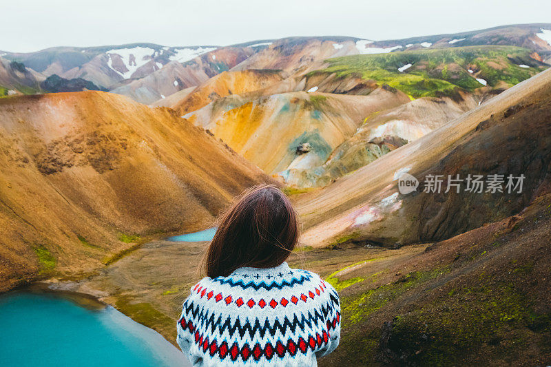 女游客在荒野中欣赏五彩缤纷的彩虹山和绿松石湖