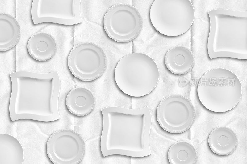 一套不同的盘子孤立和重复在白纸桌布背景
