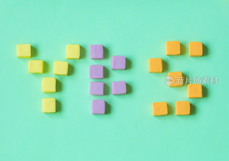 “是的”这个词写在五颜六色的立方体糖果上。
