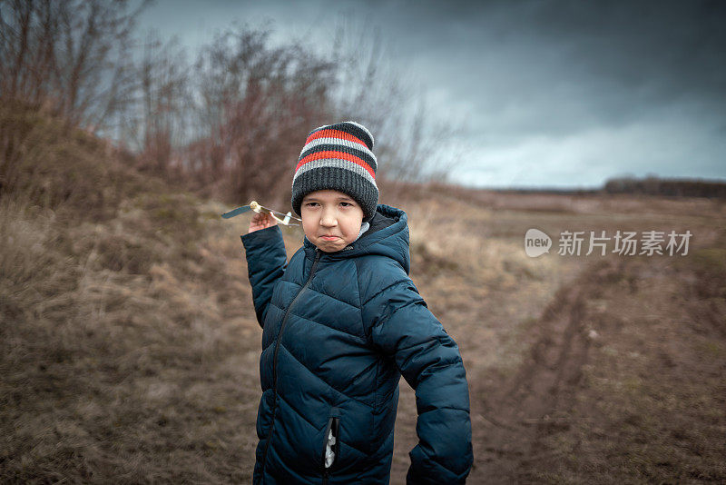 非常严肃的男孩正在室外扔他的手工飞机