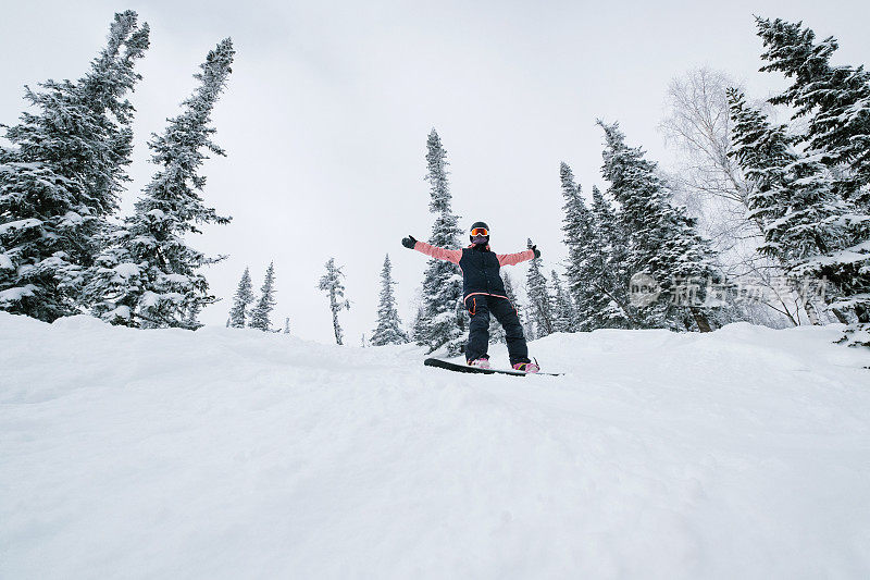 在冬日白雪覆盖的森林，新鲜的雪粉，阳光明媚的冬日里，自由骑手骑着滑雪板