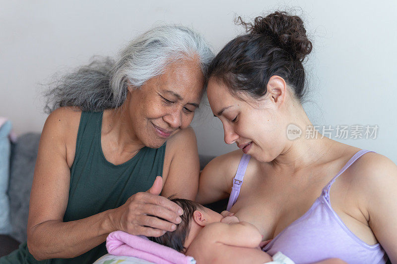 一位年轻的母亲在给婴儿喂奶时得到了母亲的鼓励