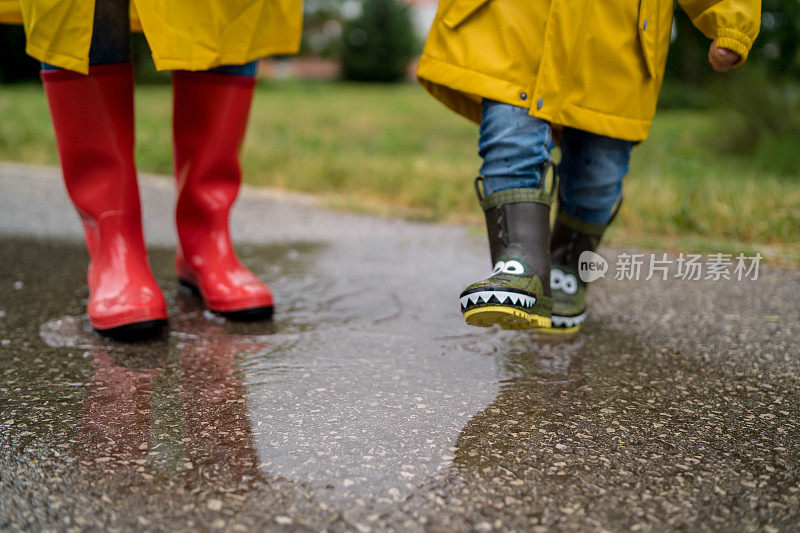 母亲和一个孩子。母亲和儿子穿着雨衣，手牵着手在公园里