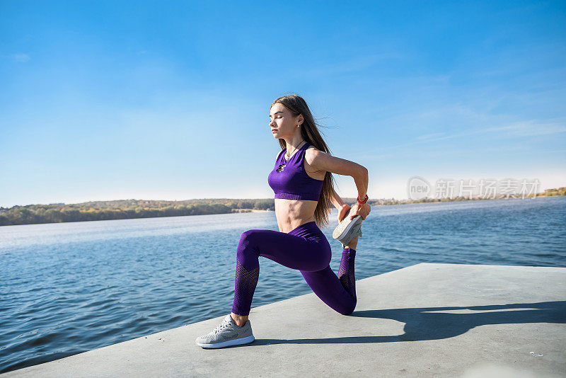 一个爱运动的年轻女子白天在湖边做健身运动。健康的生活方式的概念。