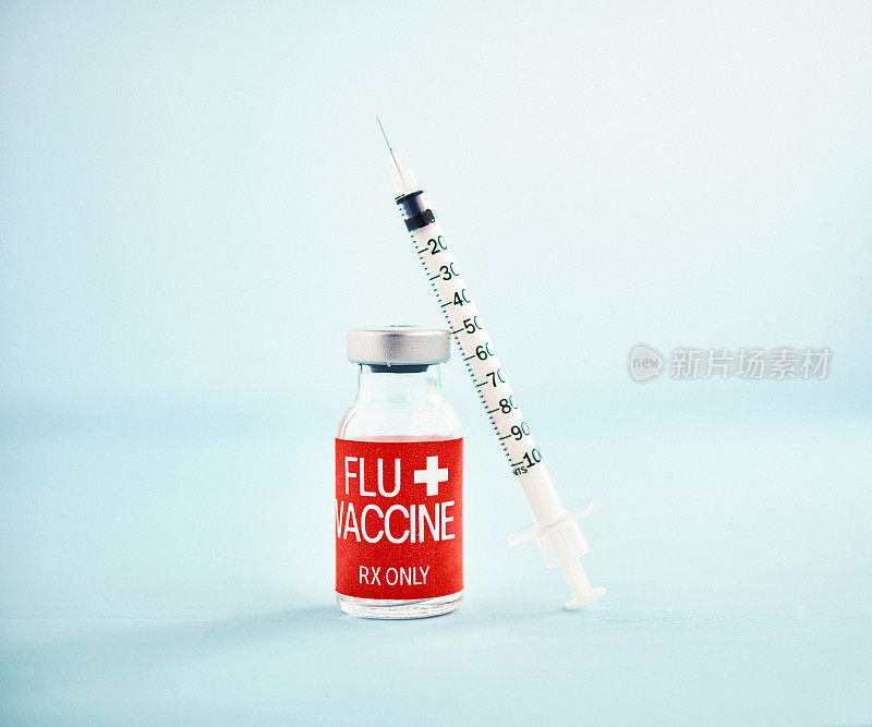 亮蓝色背景上带注射器的流感疫苗小瓶