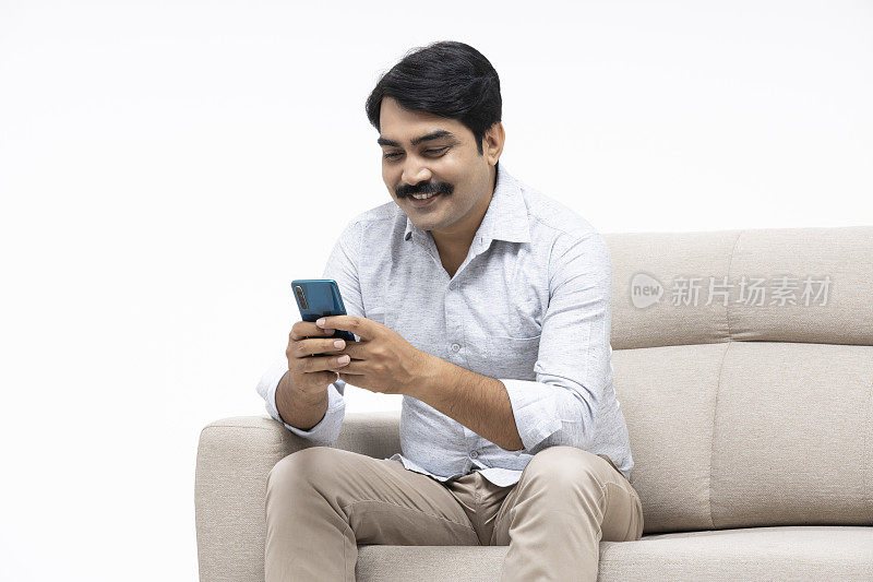 成熟的男人坐在沙发在白色的背景，库存照片