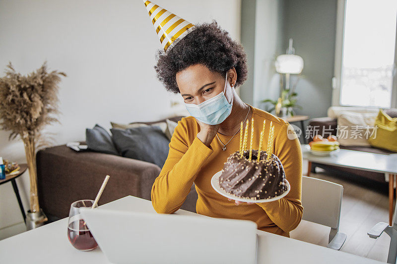 一位戴着面具的非洲妇女在视频通话中庆祝生日