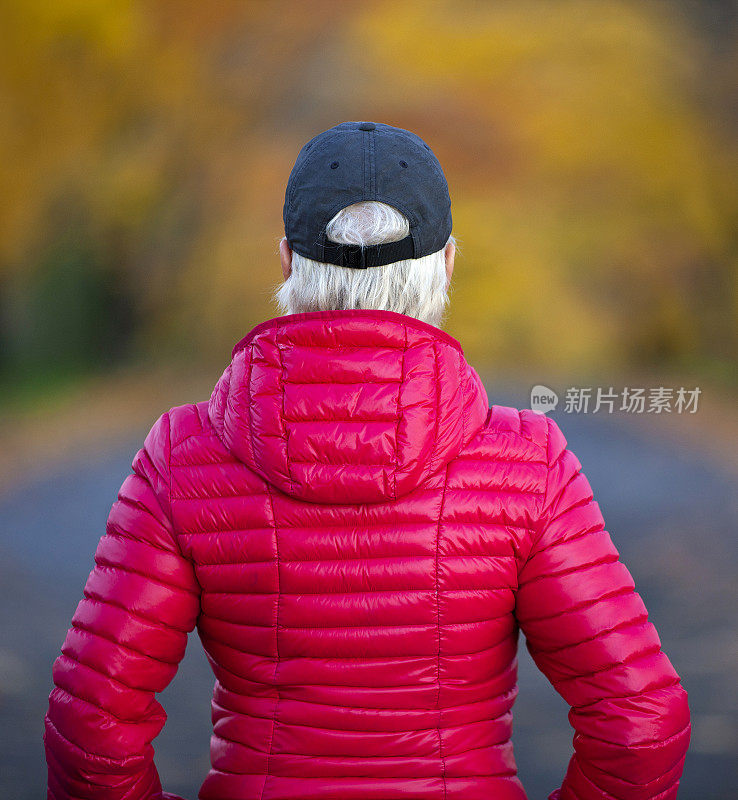 一个女人在路上看着秋天的树叶。