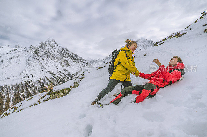 一对年轻的徒步旅行者在白雪皑皑的山脊上嬉戏