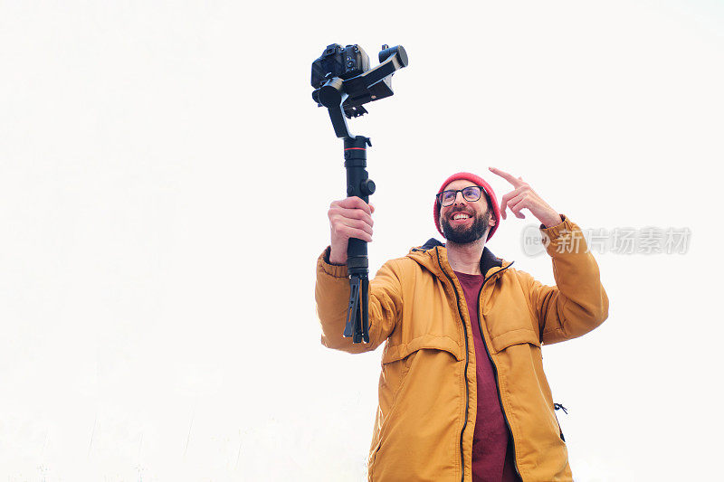 摄影师拍摄自己与一个机动万向架上的单反相机与白色背景