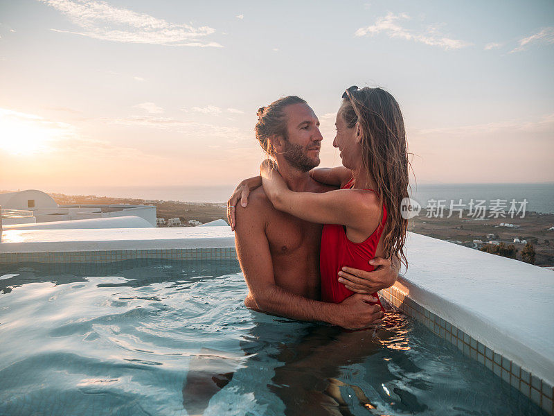 夕阳西下，一对可爱的情侣在热水浴缸里拥抱