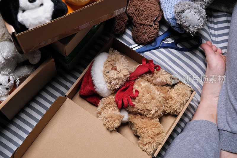 一个女人正坐在床上，装着要捐赠的毛绒玩具