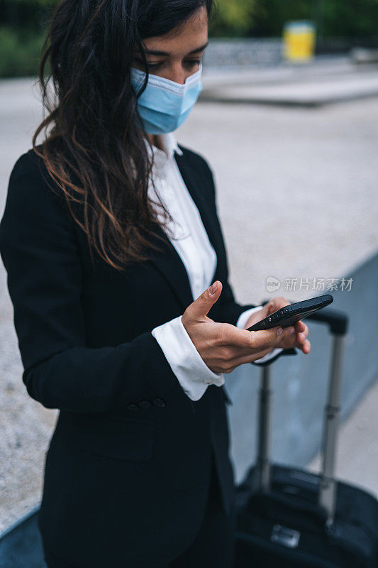 年轻的旅行商人使用手机，防护口罩