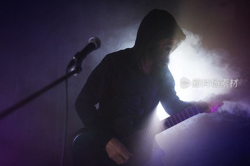 重金属摇滚吉他手在舞台灯光下表演吉他
