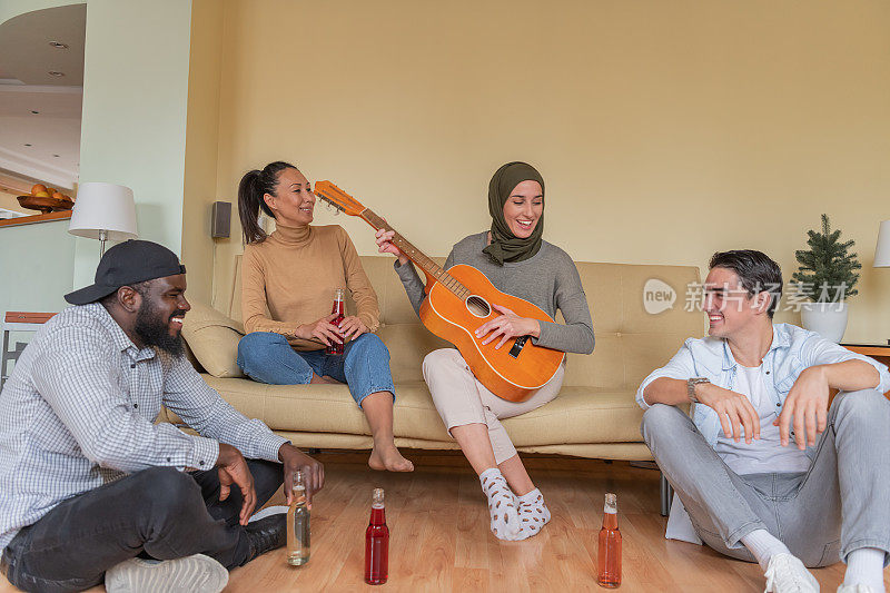 一群不同种族的朋友在家里弹吉他喝啤酒。